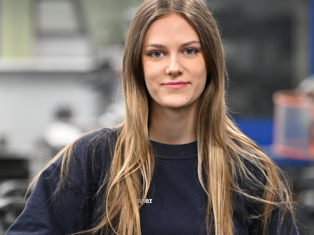 Isabelle macht eine Ausbildung zur Mechatronikerin. Sie steht in einer Werkstatt.