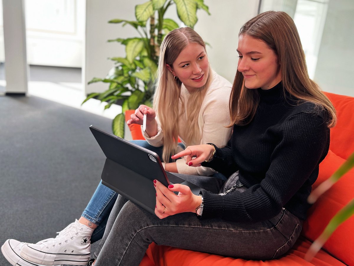 Zwei junge Frauen sitzen auf einem Sofa und schauen etwas auf einem Tablet an Zwei junge Frauen sitzen auf einem Sofa und schauen etwas auf einem Tablet an