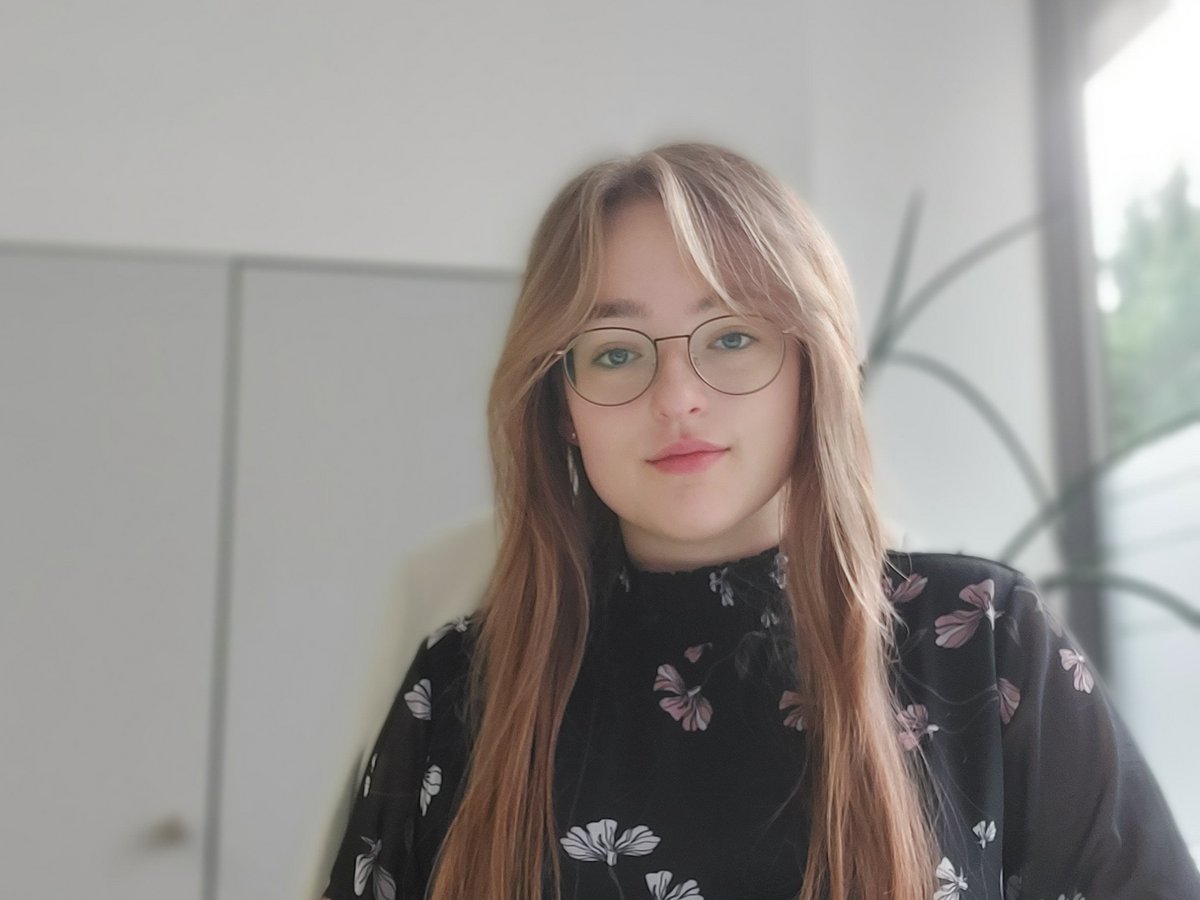 Eine junge Frau sitzt vor einem Schrank Lina ist Auszubildende als Bankkauffrau und Azubi-Blogger.