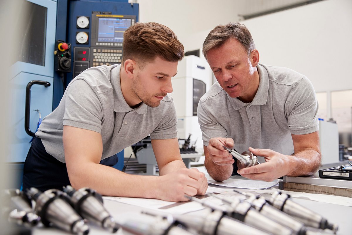 Junger Mann und Ausbilder arbeiten mit Metallteilen für die Industrie Industriemechaniker/-in bei HEUFT SYSTEMTECHNIK GMBH