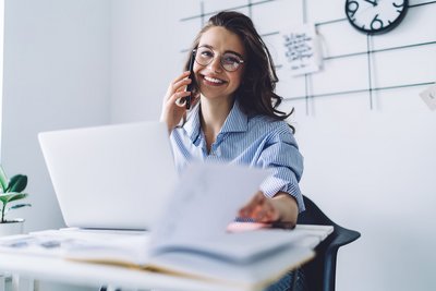 Junge Frau arbeitet in einem Büro und telefoniert. Sie macht eine Ausbildung.