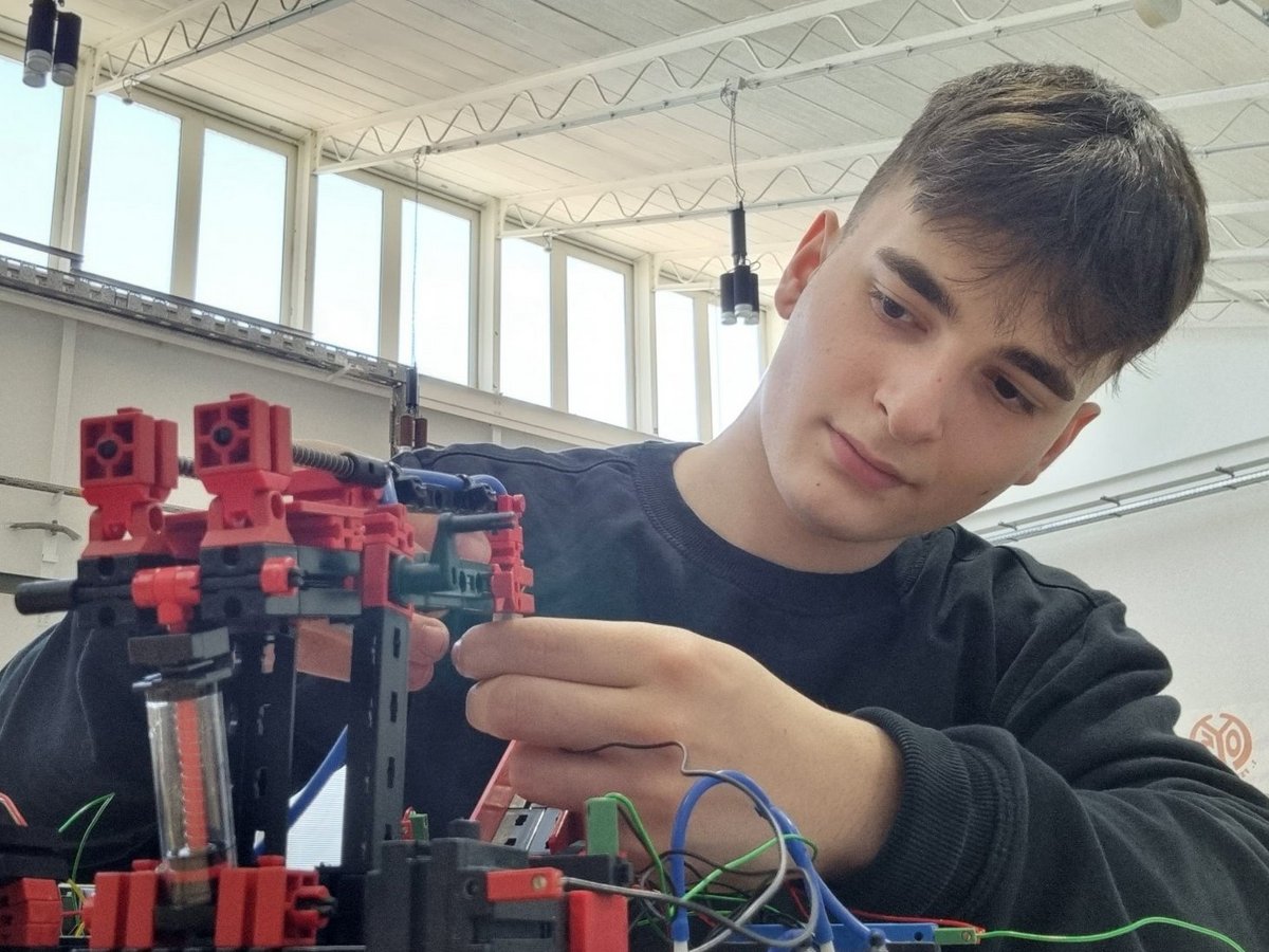 Azubi Ilhan arbeitet an einem kleinen Roboter.