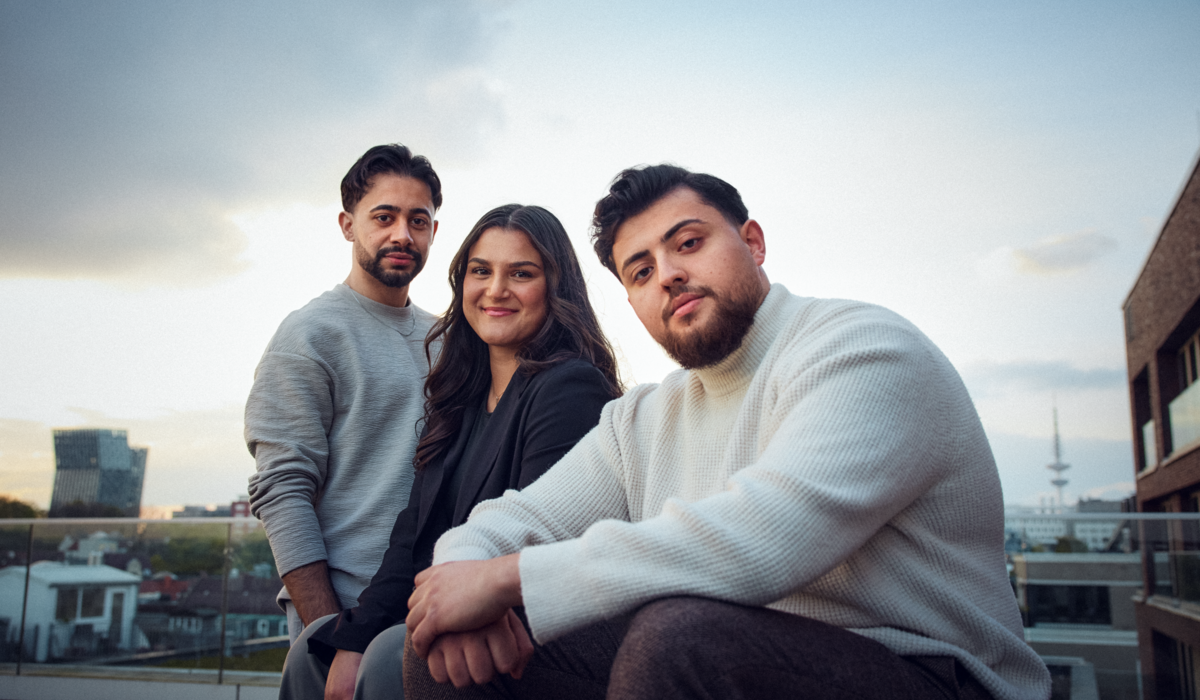 Gemo, Mo und Feyza sind Botschafter für die Ausbildung. Der IHK Azubi Kampagne könnenlernen. Alle drei sitzen draußen auf einer Dachterasse.