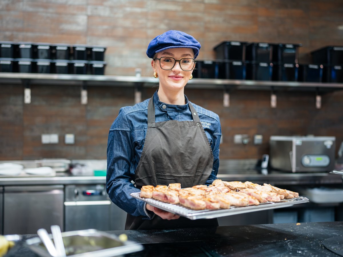 Azubi Bloggerin Fee macht eine Ausbildung zur Köchin. Sie steht im Ausbildungsbetrieb in der Küche und bereitet Essen vor.